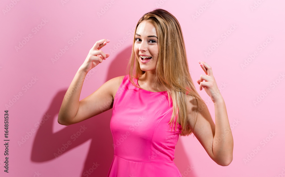 Young woman crossing her fingers and wishing for good luck