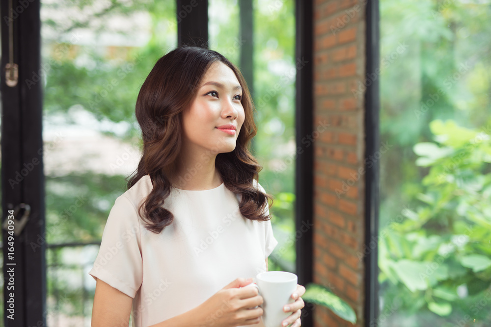 美丽的亚洲女人在家客厅透过窗户微笑的肖像