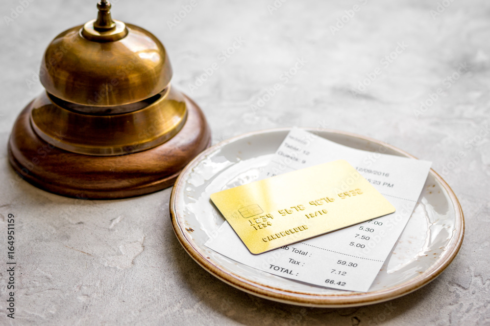 credit card for paying, waiter ring and check on cafe stone desk background