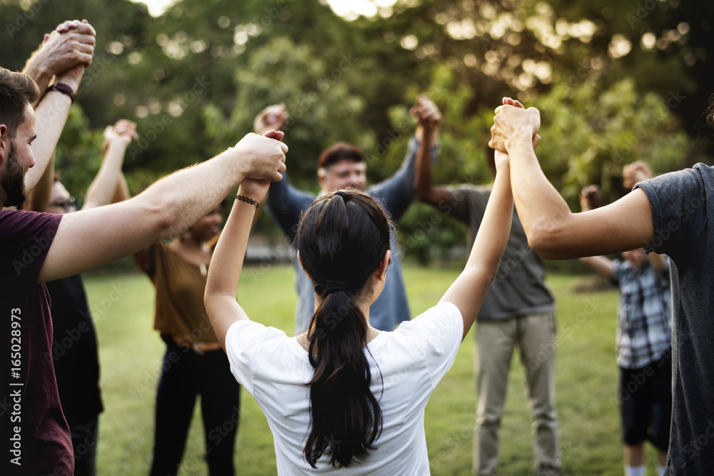 Group of people holding hand together in the park