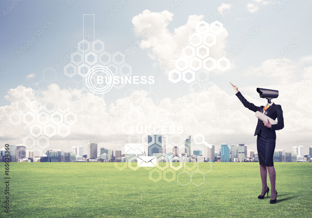 Camera headed woman standing on green grass against modern citys