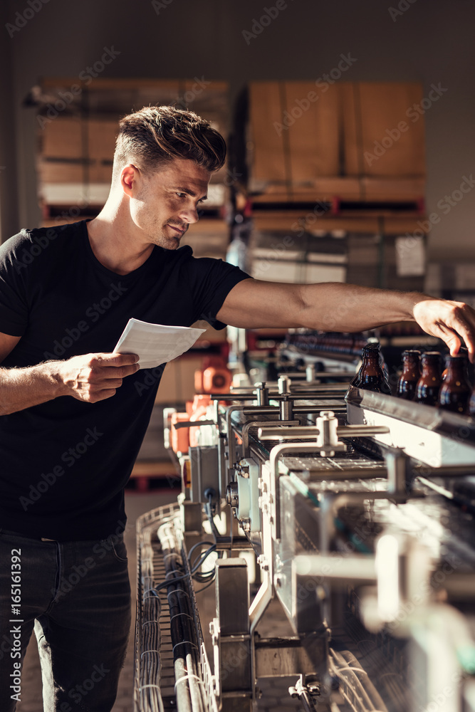 Man supervising the process of beer bottling at brewery