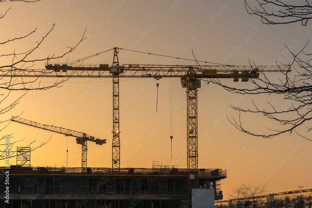 Industrial construction cranes and building silhouettes