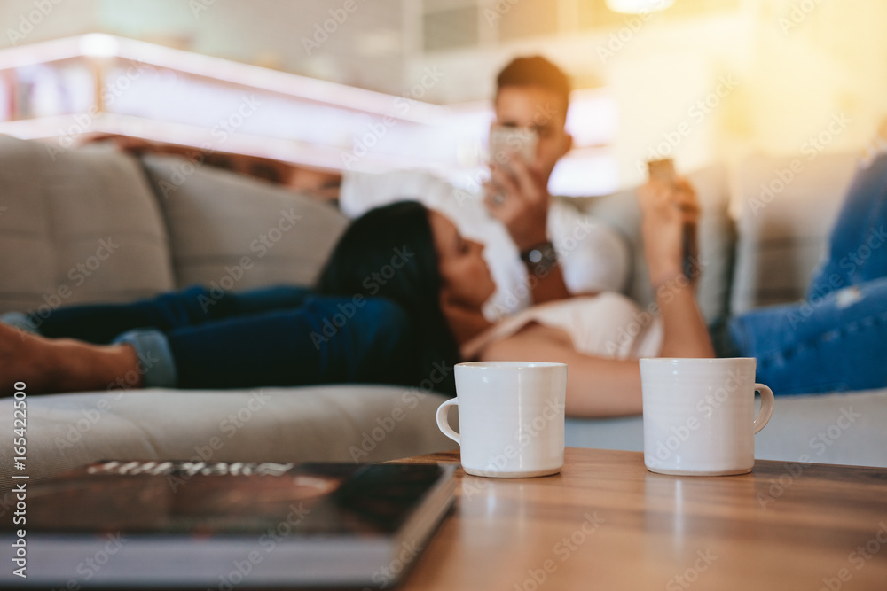 Coffee cups on table with couple relaxing in background