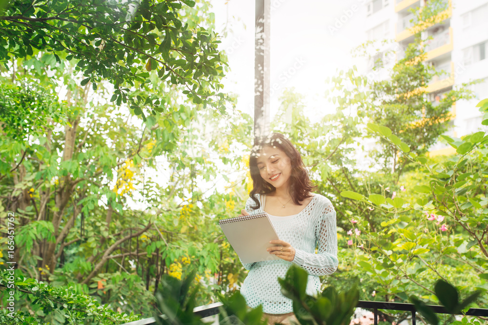 Young attractive sweet girl with notepad on a veranda. Spring mood.