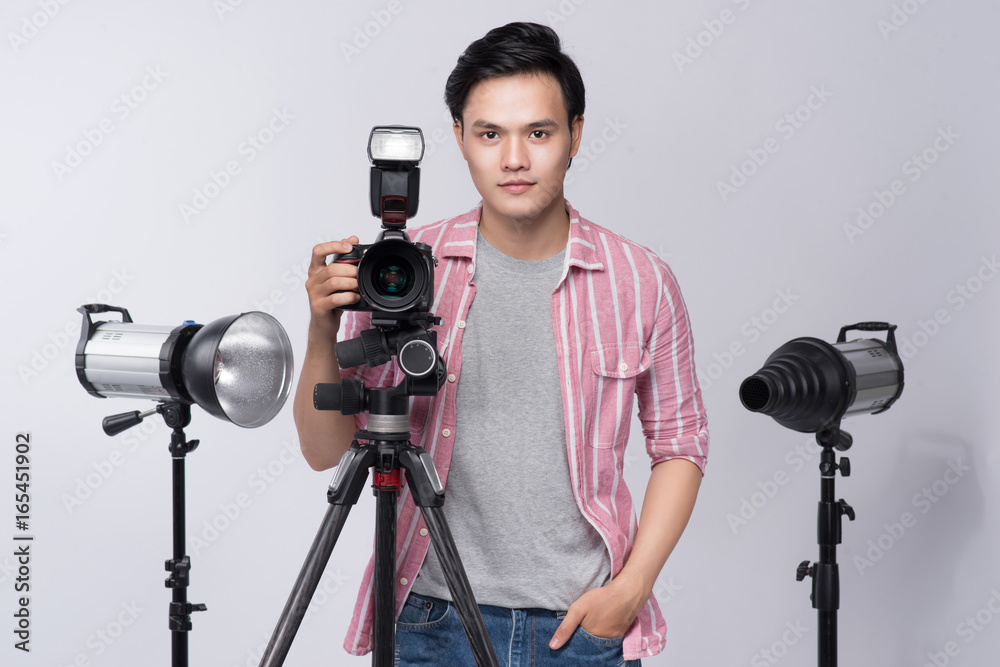 Young asian photographer holding digital camera, while working in studio