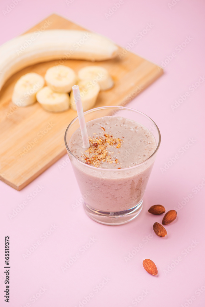 Fresh made banana smoothie in a glass on pink background