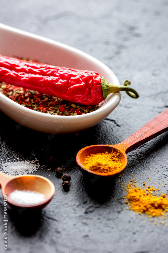 spices in wooden spoon on dark background