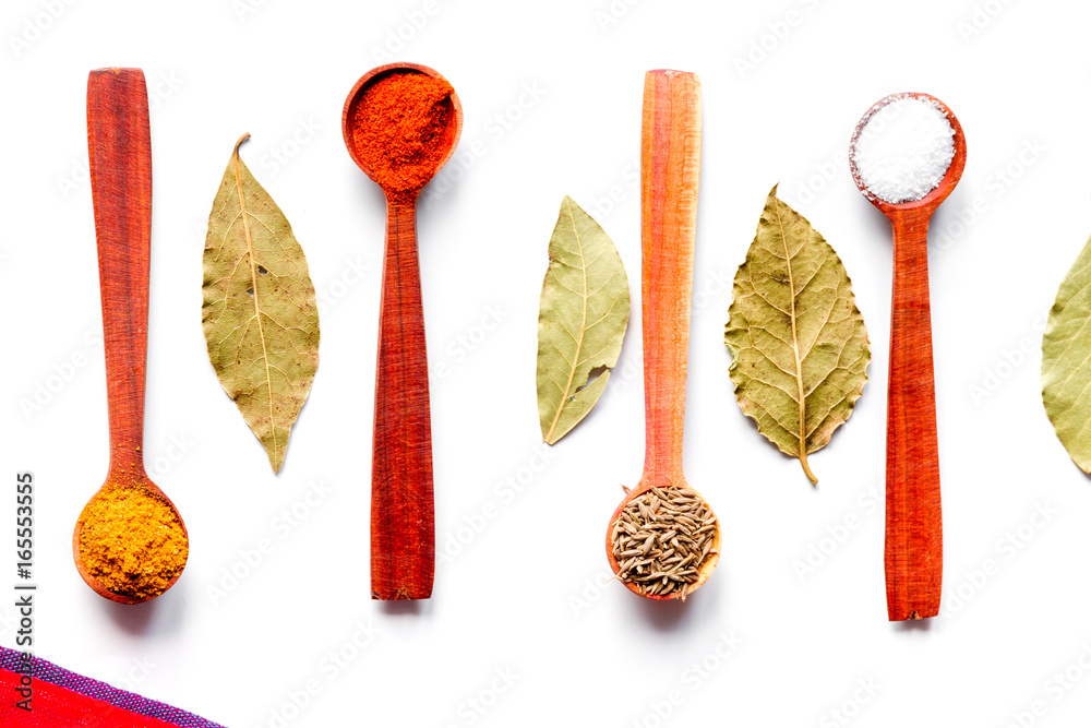 spices in wooden spoons on white background top view