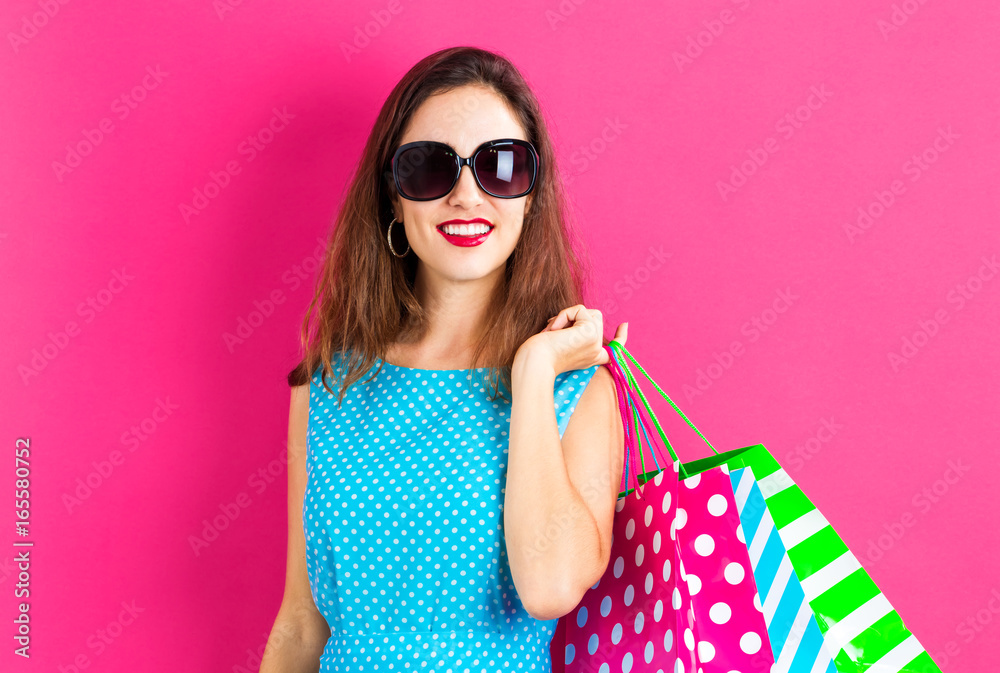 Happy young woman holding shopping bags on a pink background