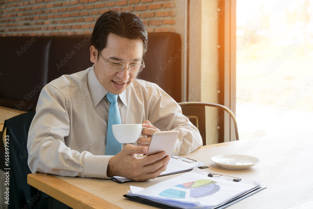 Businessman boss in casual shirt checking e-mail via cellphone before meeting with staff. Male profe