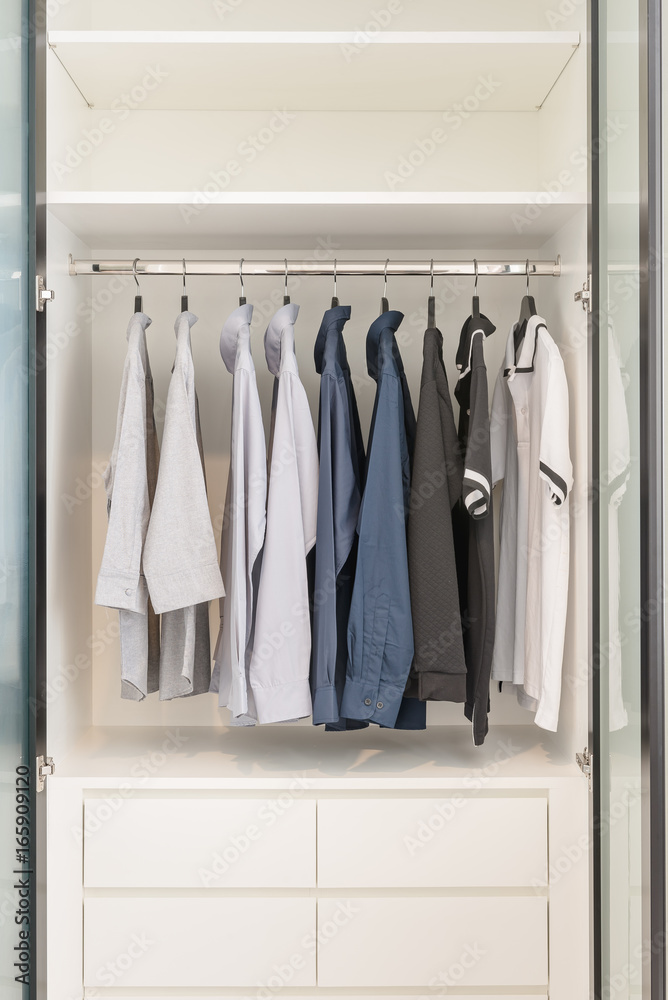 clothes hanging on rail in wooden white wardrobe