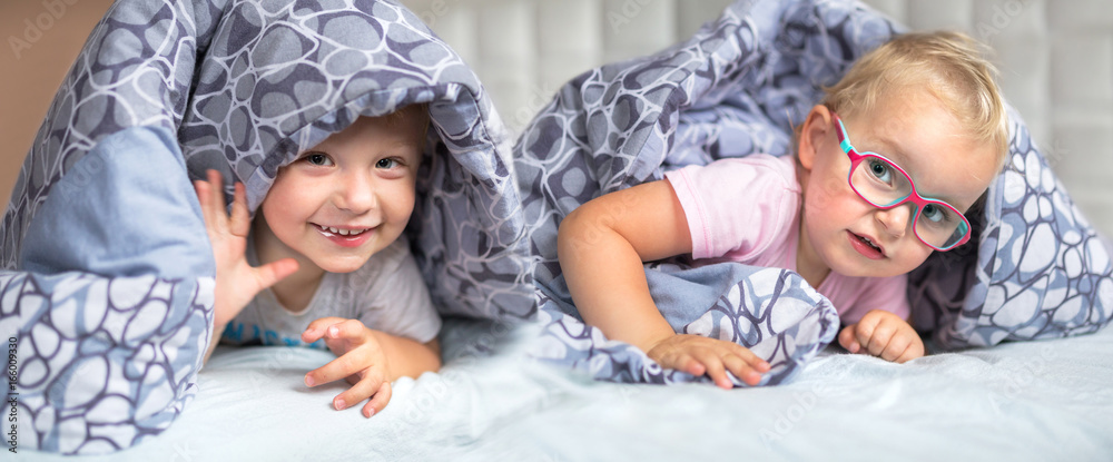 Baby boy and girl twins hiding in parents bed