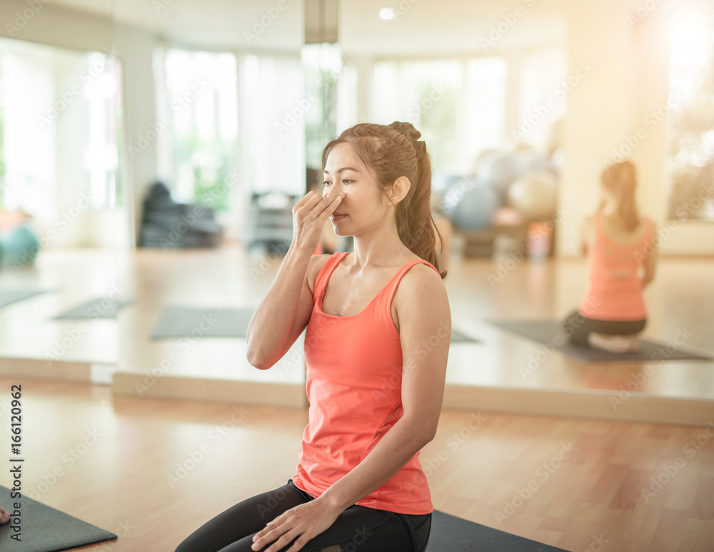 woman yogi practicing yoga, sitting in Padmasana, Lotus pose, using Alternate Nostril Breathing, nad