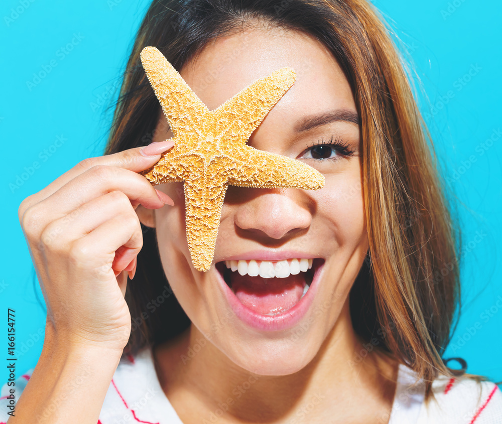 Happy woman summer theme with a starfish held up to her face