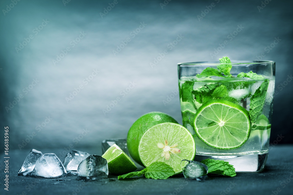 Close up the fresh mojito cocktail with fresh lime and mint leaf on black stone background