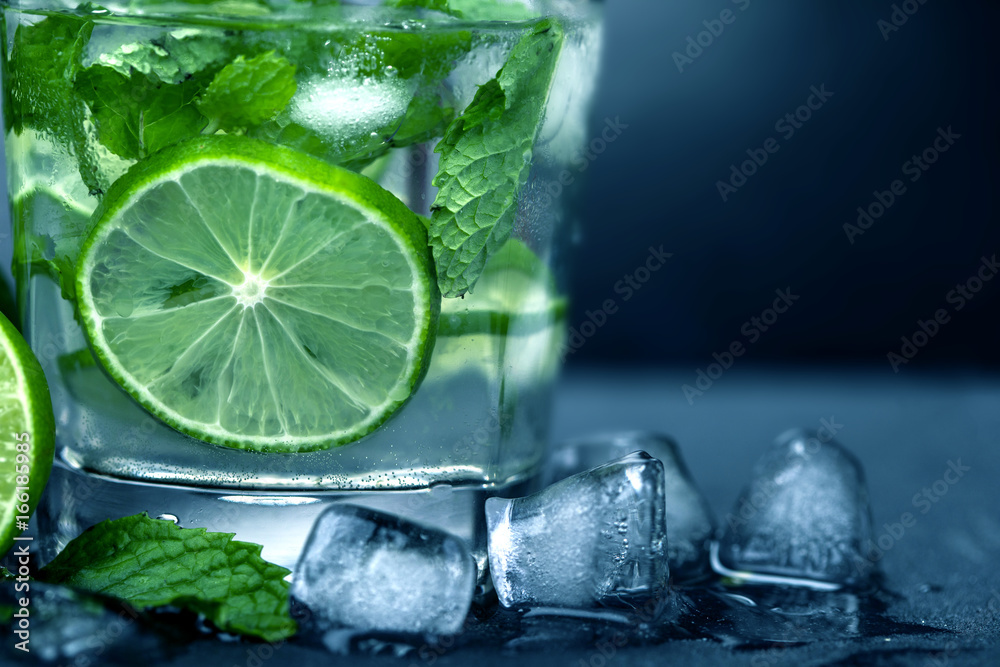 Close up the fresh mojito cocktail with fresh lime and mint leaf on black stone background