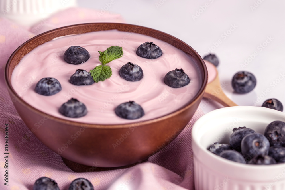 close up the  pink creamy homemade blueberries fruit yogurt with fresh green mint leaf on wooden tab