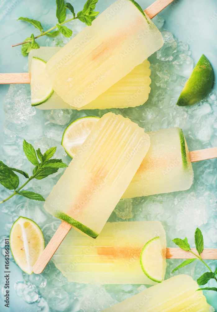 Summer refreshing lemonade popsicles with lime and mint with chipped ice over blue background, top v