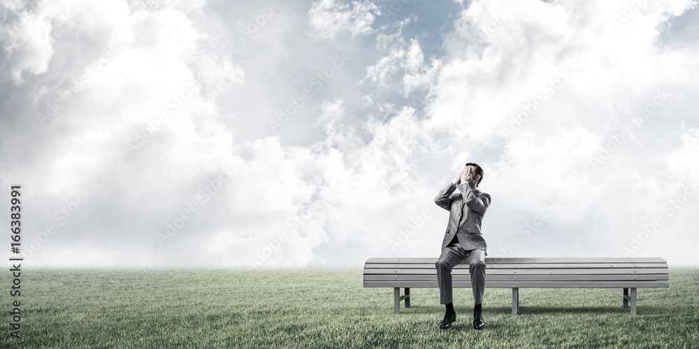 Young man in summer park on bench do not want to see anything