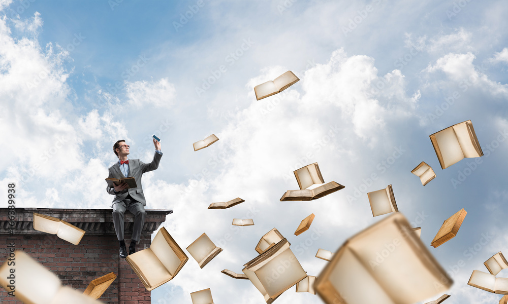 Young businessman or student studying the science and books flying around