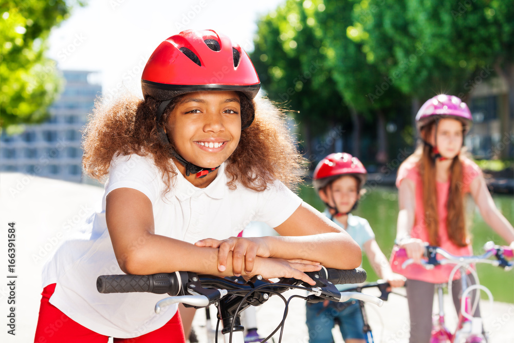 Happy African girl riding bicycle in summer city