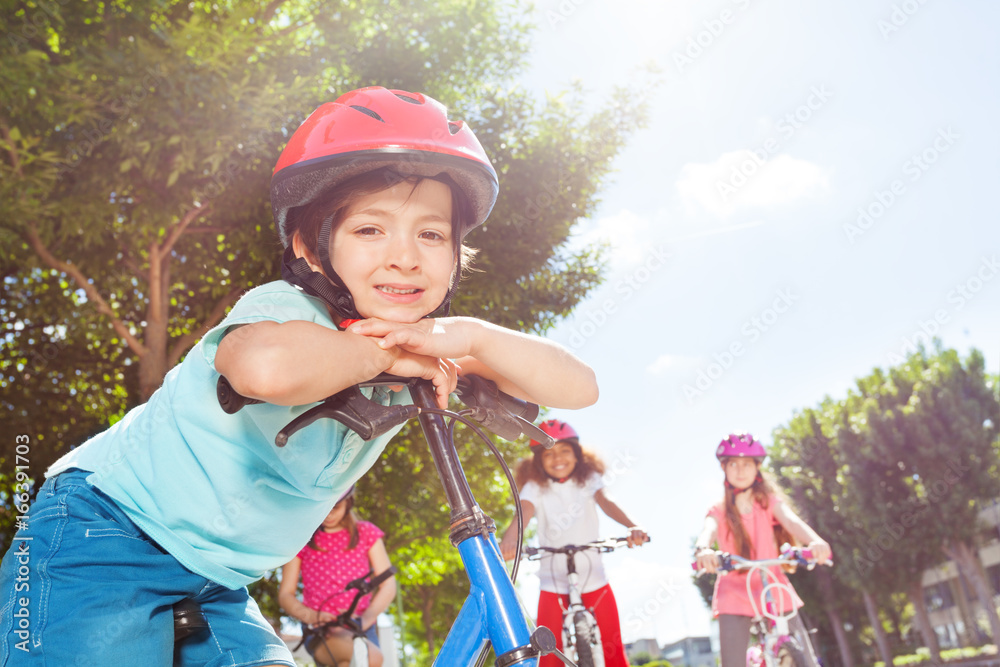 Smiling boy standing with bicycle at summer park