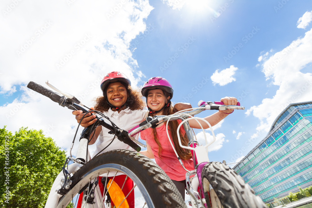 happy girl-friends hugging and holding bicycles