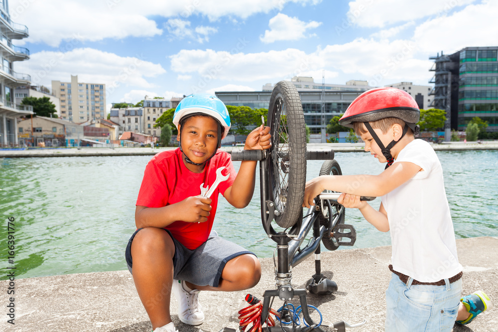 Two little mechanics repairing bike outdoors