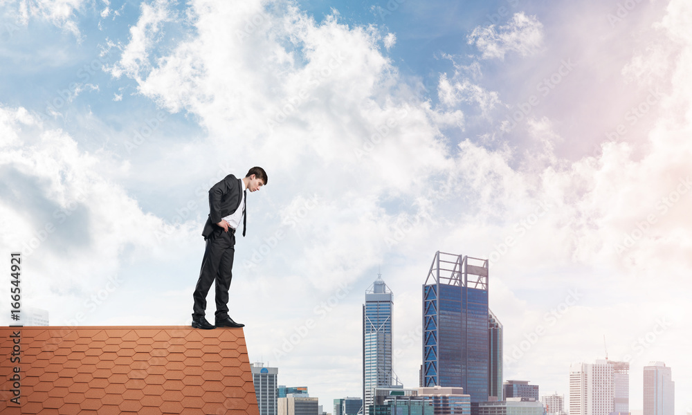 Businessman looking down from roof and afraid to make step. Mixed media