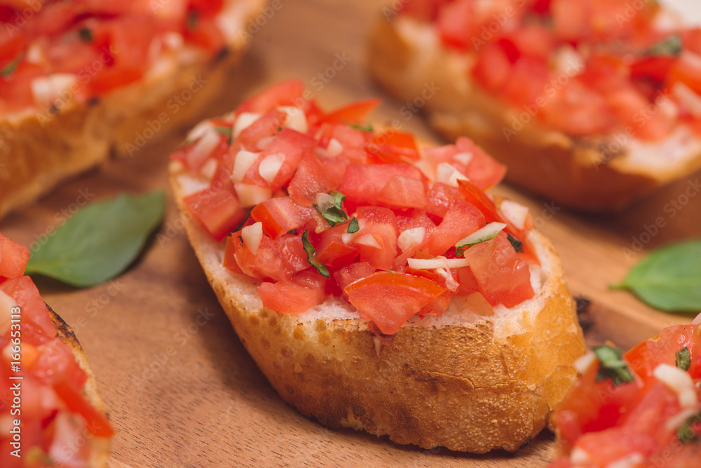 Tasty Italian bruschetta with  bread topped with tomato and herbs on wooden board