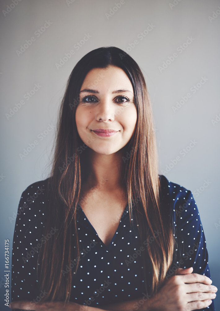 Smiling young businesswoman standing alone with her arms crossed