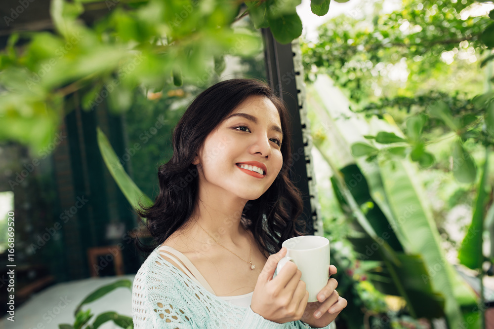 漂亮的越南女人在阳台上享受早晨的咖啡