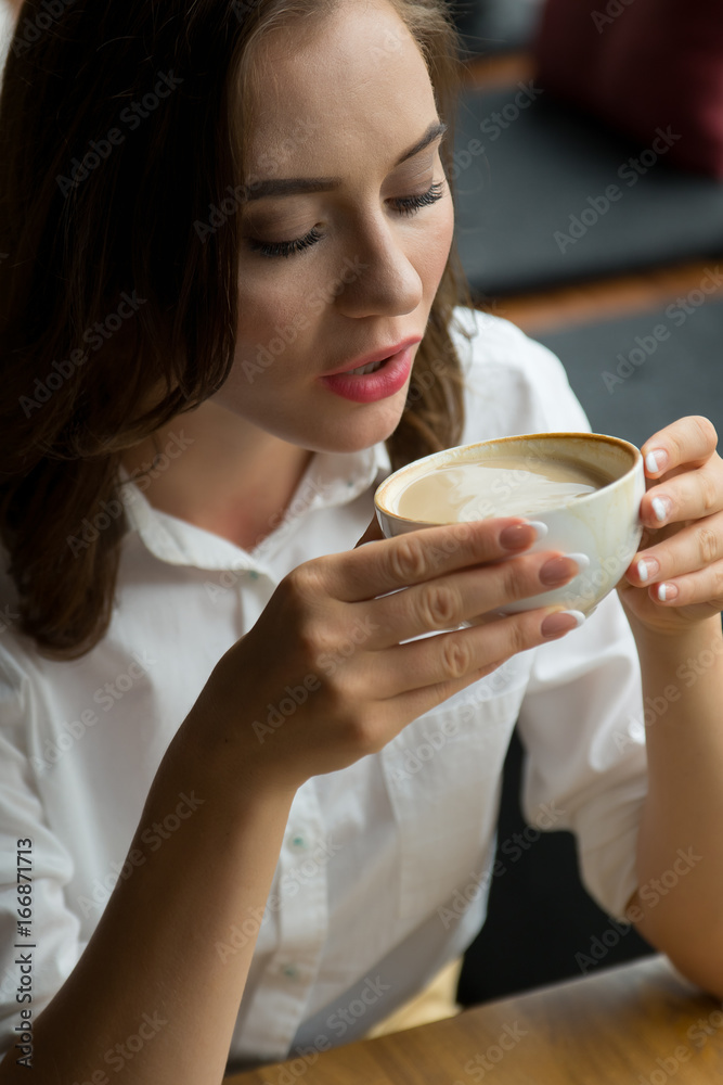 年轻漂亮女人在咖啡店喝咖啡的特写。