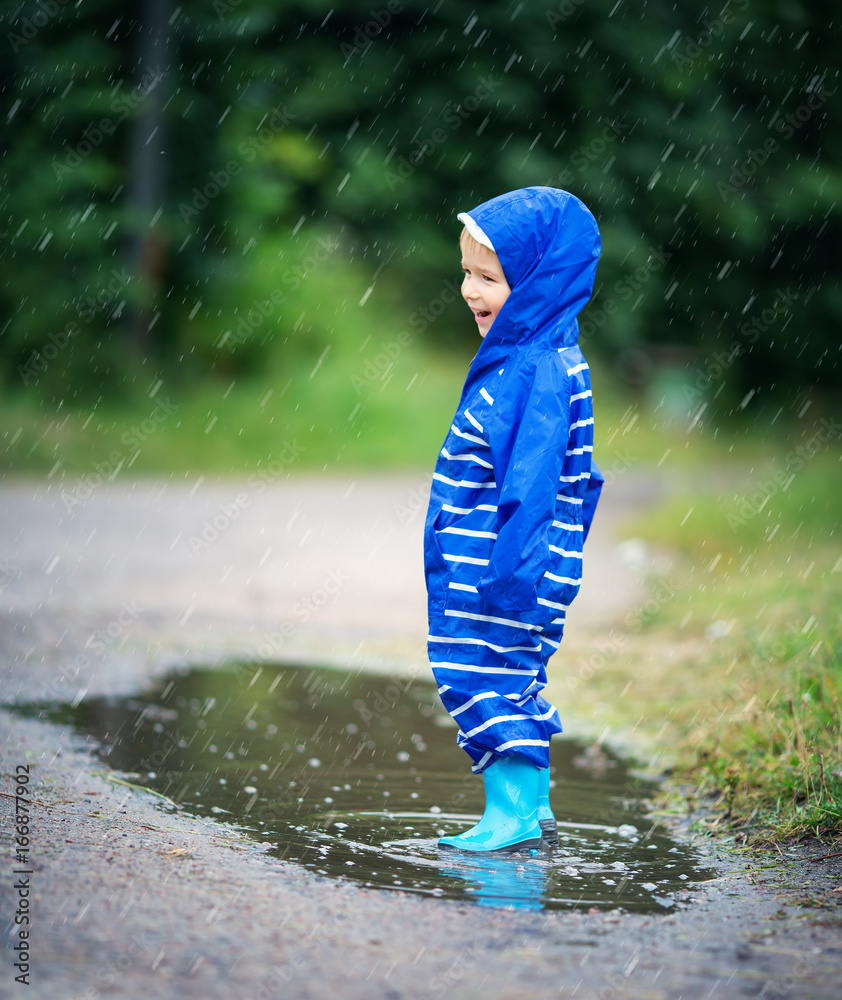 雨天孩子穿着雨鞋在水坑里行走