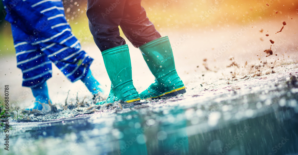 Child walking in wellies in puddle on rainy weather