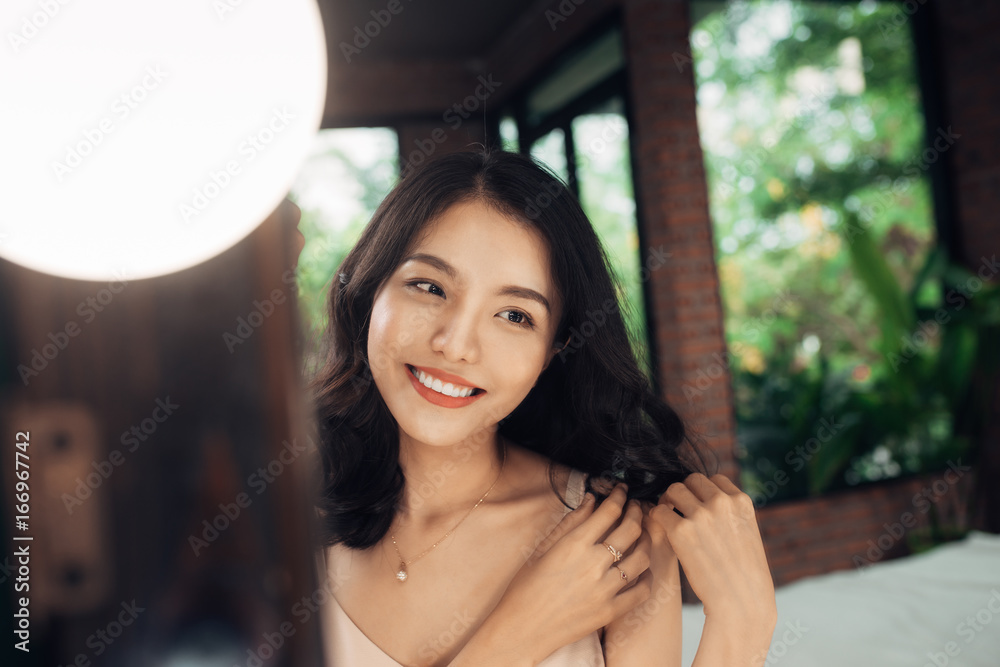 Young woman looking herself reflection in mirror at home.