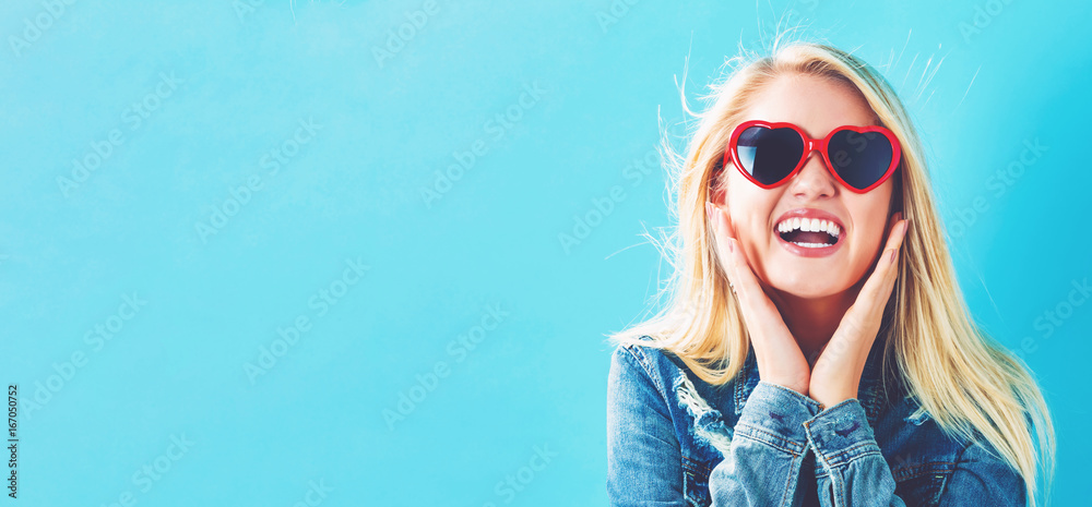 Young woman with sunglasses on a blue background