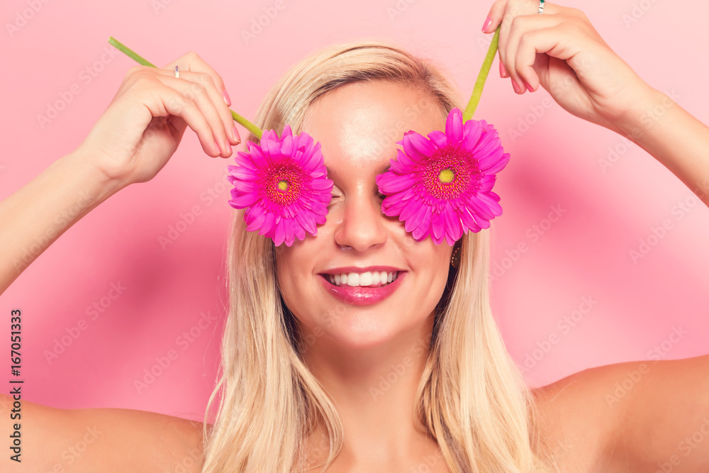 Young woman with pink garberas on a pink background