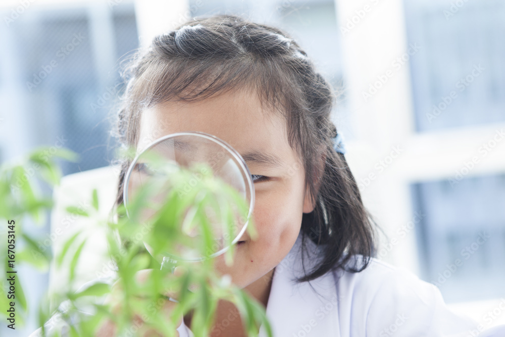 The girl is watching the plant with a magnifying glass