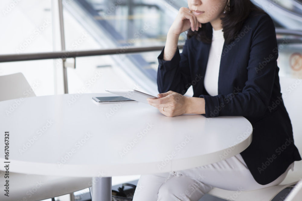 The woman is looking at the tablet in the lobby of the office building