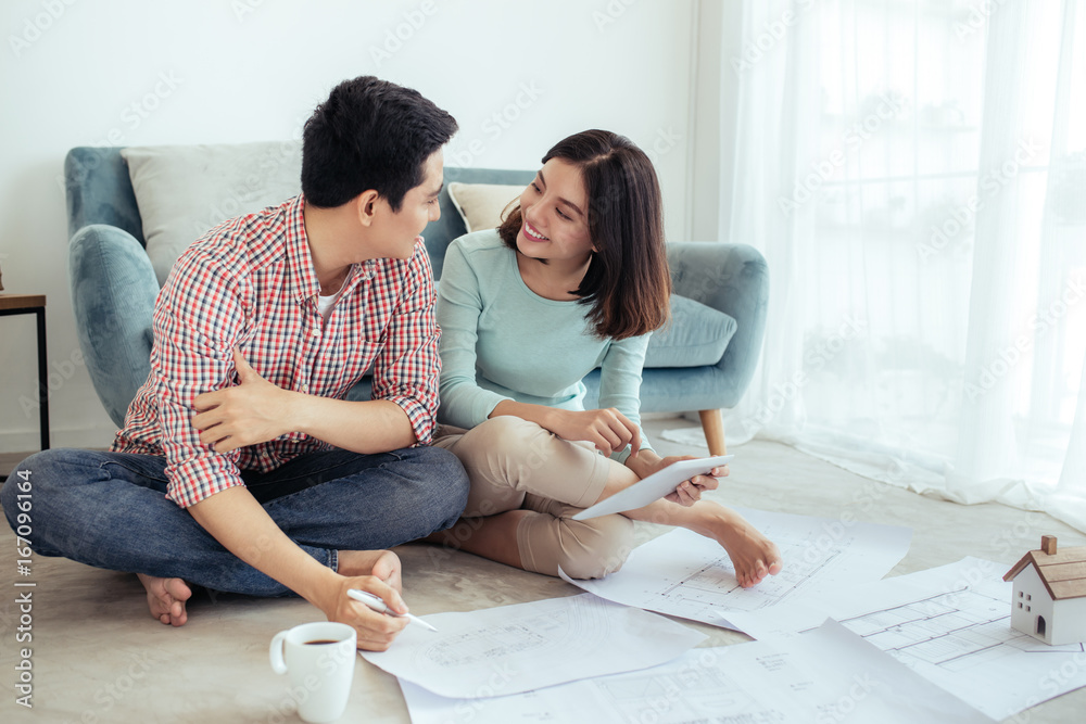 Attractive young asian adult couple looking at house plans.