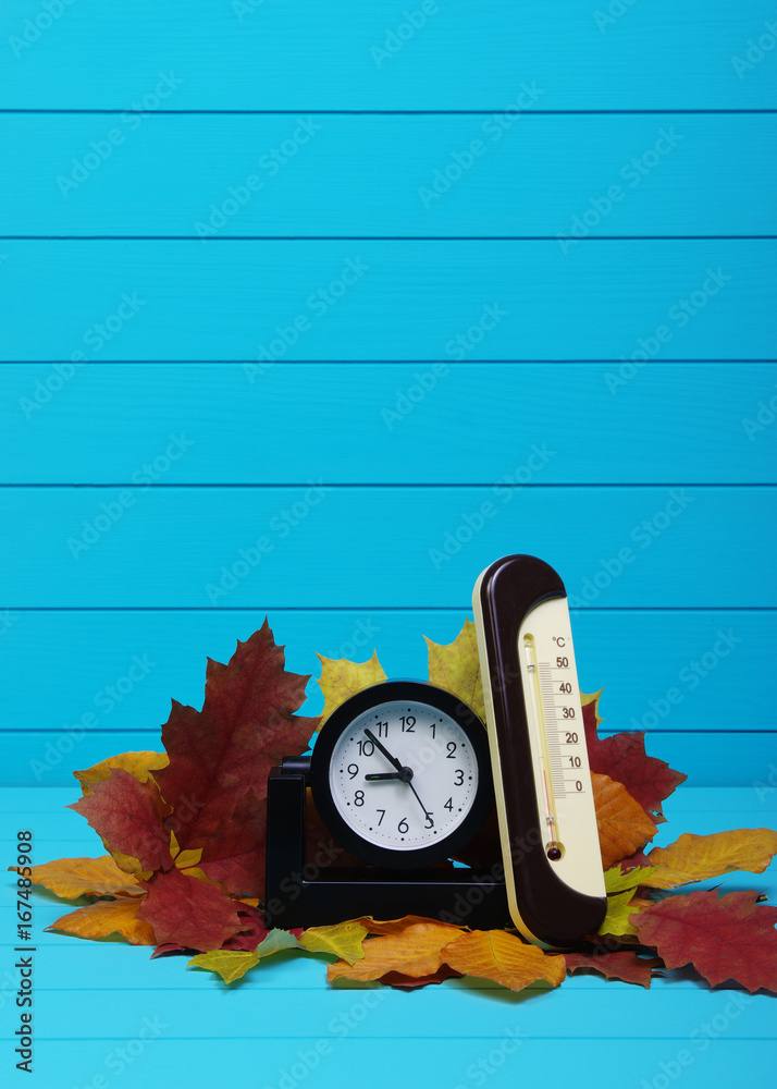 Autumn leafs and alarm clock on wood