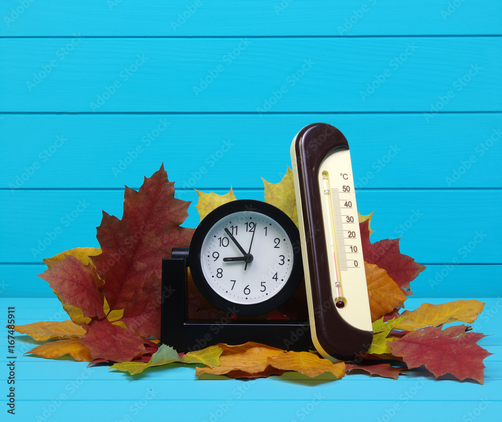 Autumn leafs and alarm clock on wood