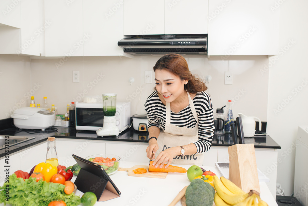 亚洲美女根据平板电脑屏幕上的食谱烹饪