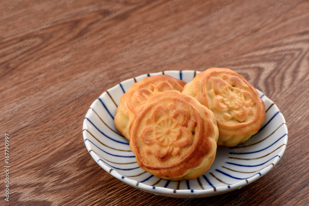 中国月饼——中国中秋节的食物，放在一个隔离在木板上的彩色盘子里