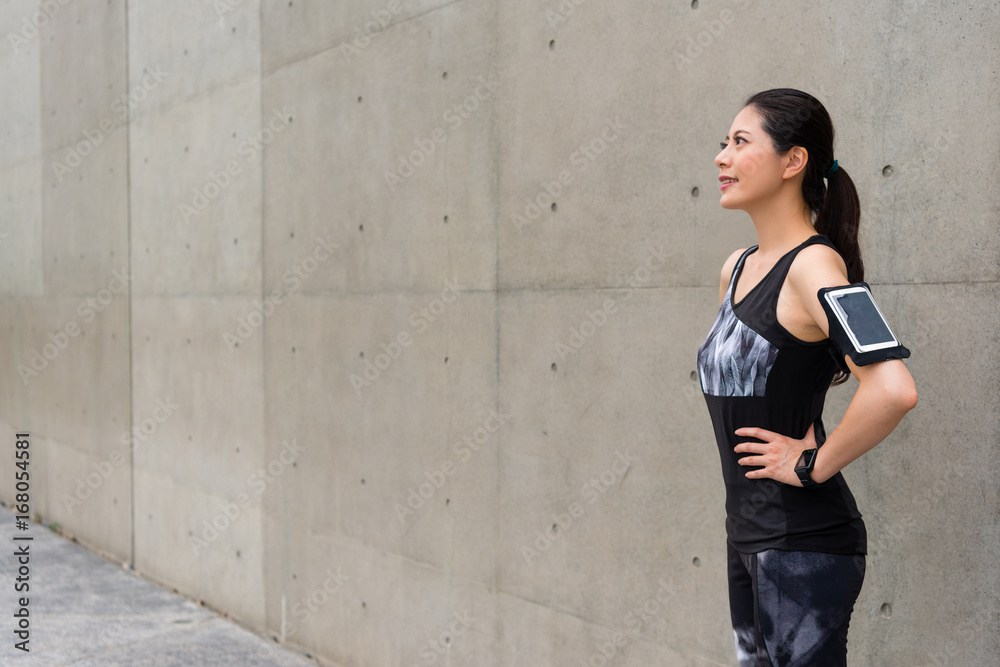 woman runner confident standing on gray wall