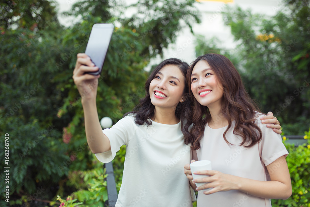 Happy young women friends well-dressed smiling while standing together