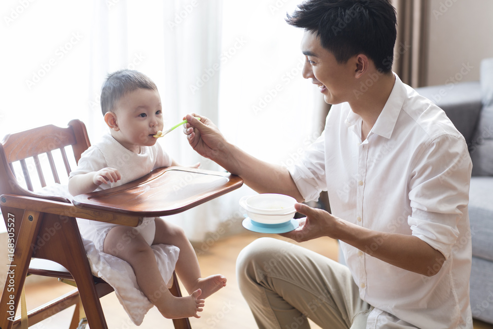 年轻的父亲喂养婴儿