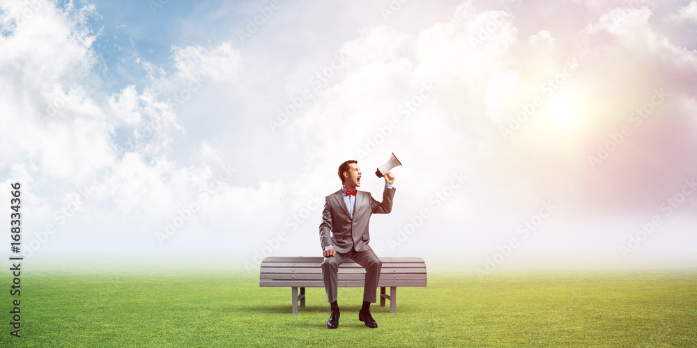 Businessman in summer park announcing something in loudspeaker